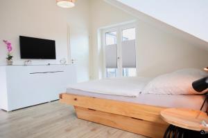 a white bedroom with a bed and a tv at Sonnengarten 11 in Kellenhusen