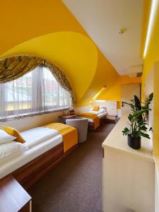 twee bedden in een kamer met een geel plafond bij Hotel Mayer Alsóörs in Alsóörs