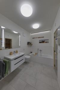 baño blanco con bañera, aseo y lavamanos en Haus Seeblick - Sonnenweg 14, en Diemelsee
