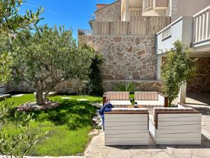 een patio met 2 stoelen en een boom in een tuin bij Villa Sania in Bol