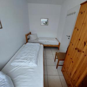 um pequeno quarto com 2 camas e uma porta de madeira em Ferienhaus Albatros em Norddeich