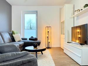 ein Wohnzimmer mit einem Sofa und einem TV in der Unterkunft Kirschgarten 3 in Kellenhusen