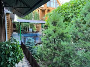 シムケントにあるКоттедж Darinaの塀と木と家のある裏庭