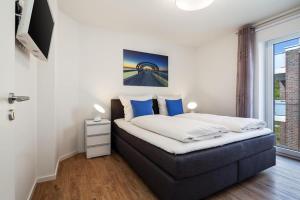 ein Schlafzimmer mit einem Bett mit blauen Kissen und einem Fenster in der Unterkunft Kirschgarten 9 - Seestern in Kellenhusen