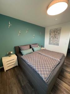 Schlafzimmer mit einem Bett mit blauer Wand in der Unterkunft Neue Liebe Haffkrug 4 in Haffkrug