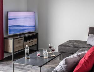 a living room with a television and glasses of wine at Neue Liebe Haffkrug 5 - Meeresstern in Haffkrug