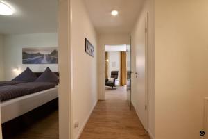 um corredor que leva a um quarto com uma cama e uma cadeira em Refugium 6 em Kellenhusen