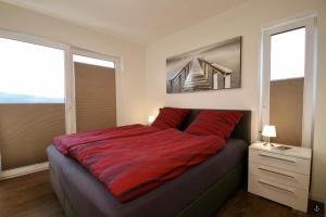 um quarto com uma cama vermelha e 2 janelas em NINA - Sonnenweg 20 em Heringhausen