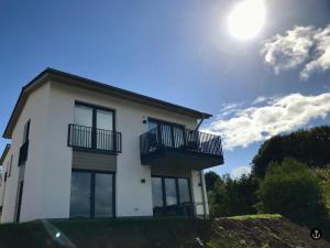 uma casa branca com varandas e o sol no céu em NINA - Sonnenweg 20 em Heringhausen