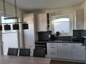 uma cozinha com armários brancos e uma mesa e cadeiras em Sonnenweg 34 em Diemelsee