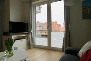 a living room with a sliding glass door with a television at Strandperle im Achterhus in Juist