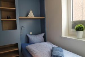 a blue room with a bed and a window at Strandperle im Achterhus in Juist