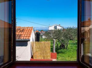 an open window with a view of a house at Apartment Serđa in Ugljan
