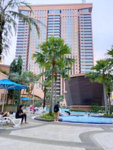 a resort pool with palm trees and a tall building at Ayan Service Suite At Times Square in Kuala Lumpur