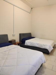 2 camas en una habitación con sábanas blancas en Jungle Ippie Hostel, en Tanah Rata