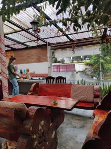a patio with a wooden table and a woman in a kitchen at Jungle Ippie Hostel in Tanah Rata
