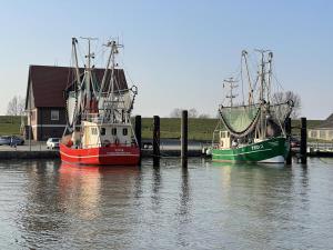 two boats are docked at a dock in the water at Am Kutterhafen 17 - HAFENGLÜCK in Fedderwardersiel