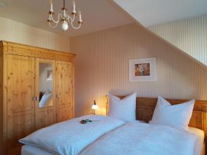 sypialnia z łóżkiem z białą pościelą i żyrandolem w obiekcie Lütten Uttied w mieście Gollwitz