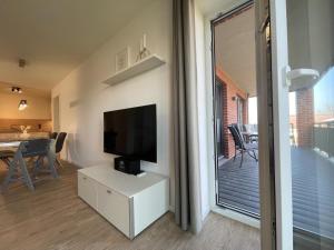 ein Wohnzimmer mit einem TV und einem Tisch mit Stühlen in der Unterkunft Hansehaus 6 in Grömitz
