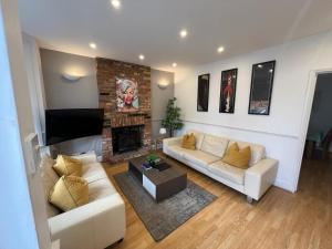 a living room with two couches and a fireplace at Great 4 bedroom House - Great Location - Garden - Parking - Fast WiFi - Smart TV - Newly decorated - sleeps up to 8! Only 10 mins drive to Sandbanks Beach! Close to Poole & Bournemouth in Parkstone