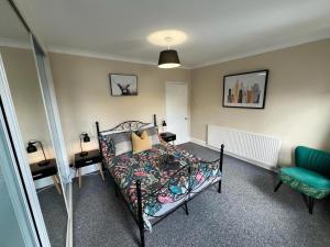 a bedroom with a bed and a blue chair at Great 4 bedroom House - Great Location - Garden - Parking - Fast WiFi - Smart TV - Newly decorated - sleeps up to 8! Only 10 mins drive to Sandbanks Beach! Close to Poole & Bournemouth in Parkstone