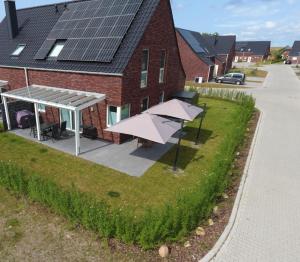 a house with a solar roof and a patio with an umbrella at Am Kutterhafen 8a - Wattenmeer-Oase in Fedderwardersiel