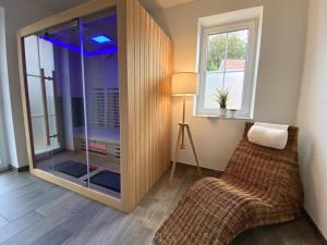 a room with a glass shower with a chair and a window at Meerglück CUX in Cuxhaven