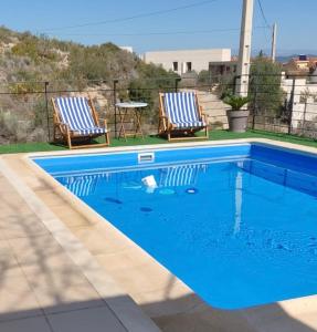 a swimming pool with two chairs and a table at 3 Bed Chalet-Pool-Pets-Hot Tub-Parking-Garden in Chiva