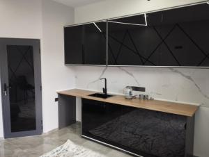 a kitchen with a wooden counter and black cabinets at Lumi in Bishkek