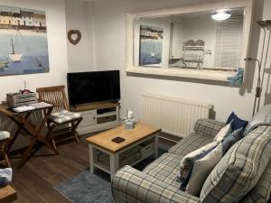 a living room with a couch and a tv at Seashell Cottage in Whitby