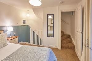 a bedroom with a bed and a staircase with a mirror at Seashell Cottage in Whitby +4 photos