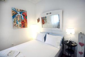 Schlafzimmer mit einem weißen Bett und einem Spiegel in der Unterkunft The Red House in Dassia in Dassia