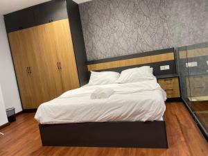ein Schlafzimmer mit einem großen Bett mit weißer Bettwäsche in der Unterkunft The Place Cyberjaya Duplex with Putrajaya View in Cyberjaya