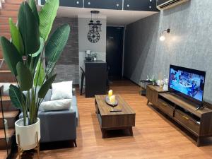 ein Wohnzimmer mit einem Sofa und einem TV in der Unterkunft The Place Cyberjaya Duplex with Putrajaya View in Cyberjaya