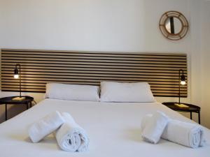 una camera da letto con un letto bianco e asciugamani di Apartamentos El Pilar Suites 3000 a Saragozza