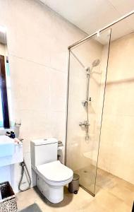 a bathroom with a toilet and a glass shower at Cozy Central Apt with Parking and Skyline View in Dubai