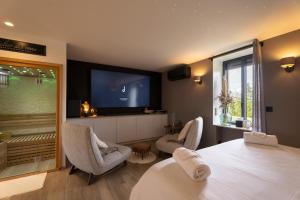a bedroom with a bed and two chairs and a tv at La Suite SPA privatif du Moulin in Saint-Laurent-dʼAndenay