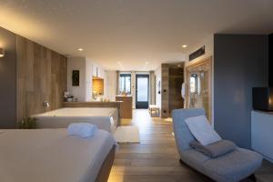 a bedroom with a bed and a couch and a kitchen at La Suite SPA privatif du Moulin in Saint-Laurent-dʼAndenay