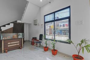 uma sala de estar com vasos de plantas e uma grande janela em OYO The Pal's Residency em Kakarmatha