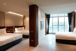 a hotel room with two beds and a window at Papoa Harbor Hotel in Kaohsiung