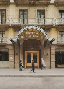 dos personas caminando frente a un hotel en Hotel Regina Barcelona, en Barcelona