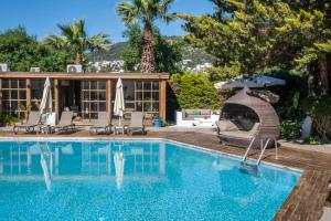 a pool with chairs and an umbrella next to a house at Costa Bodrum City in Bodrum City
