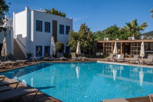 a swimming pool with chairs and umbrellas next to a building at Costa Bodrum City in Bodrum City