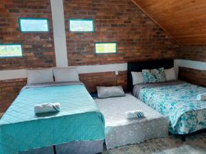 2 Betten in einem Zimmer mit Ziegelwänden und Fenstern in der Unterkunft Alojamiento en cabaña in Fúquene