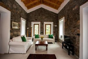 a living room with white furniture and a stone wall at Traditional stone build country house Shale in Voutás