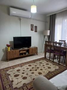 een woonkamer met een flatscreen-tv en een tafel bij Plaja 100m, bahçe katı, 1+1 daire. in Ayvalık