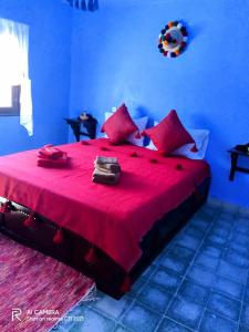 een slaapkamer met een groot rood bed met rode kussens bij Dar Sakina in Chefchaouene