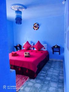 een blauwe slaapkamer met een rood bed met rode kussens bij Dar Sakina in Chefchaouene