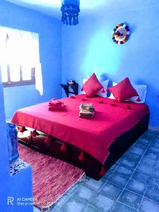 een blauwe slaapkamer met een groot rood bed met rode lakens bij Dar Sakina in Chefchaouene