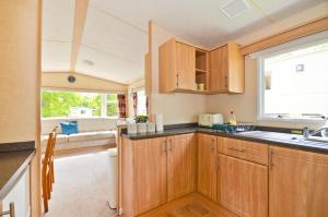 考斯的住宿－Greenwood，厨房配有木制橱柜和窗户。
